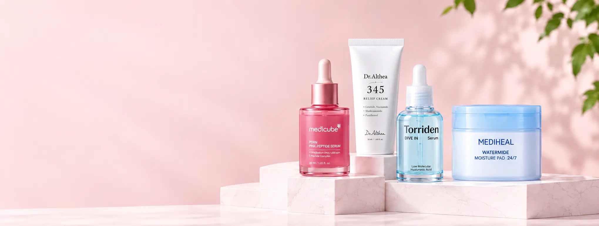 Medicube, Dr. Althea, Torriden and Mediheal Korean skincare arranged on blush stone pedestals